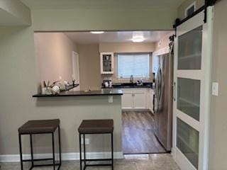 9388 Bay Colony Dr Unit 1S, Des Plaines, IL 60016 - kitchen with a kitchen bar, dark countertops, freestanding refrigerator, white cabinetry, and a peninsula