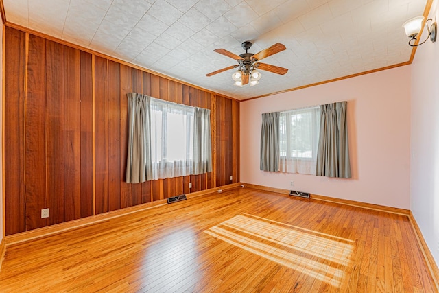 102 S Oak St, Arrowsmith, IL 61722 - empty room featuring healthy amount of natural light, wooden walls, crown molding, wood-type flooring, and ceiling fan