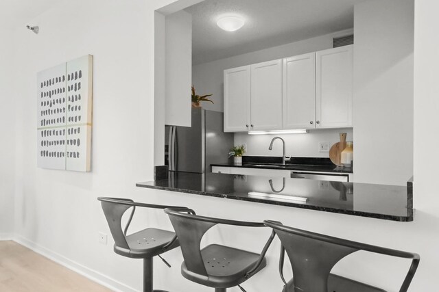 400 N Lasalle Dr Unit 2007, Chicago, IL 60654 - kitchen featuring freestanding refrigerator, white cabinets, a kitchen breakfast bar, and dark stone countertops