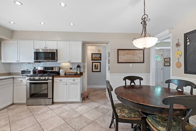 1014 Indian Rd, Glenview, IL 60025 - kitchen featuring appliances with stainless steel finishes, decorative backsplash, white cabinetry, light tile patterned floors, and hanging light fixtures