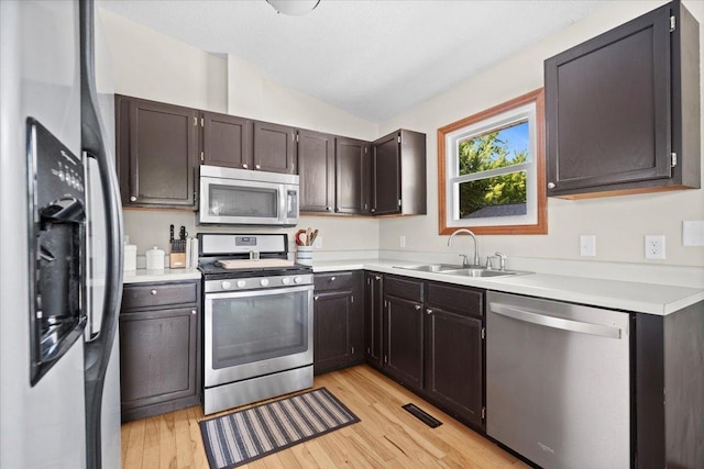 16 Rutherford Ct, Bloomington, IL 61705 - kitchen featuring stainless steel appliances, vaulted ceiling, light wood-style flooring, light countertops, and dark brown cabinets