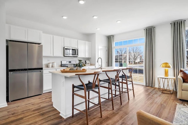 1763 Baler Ln, Aurora, IL 60503 - kitchen with appliances with stainless steel finishes, a center island with sink, light countertops, white cabinets, and a kitchen breakfast bar