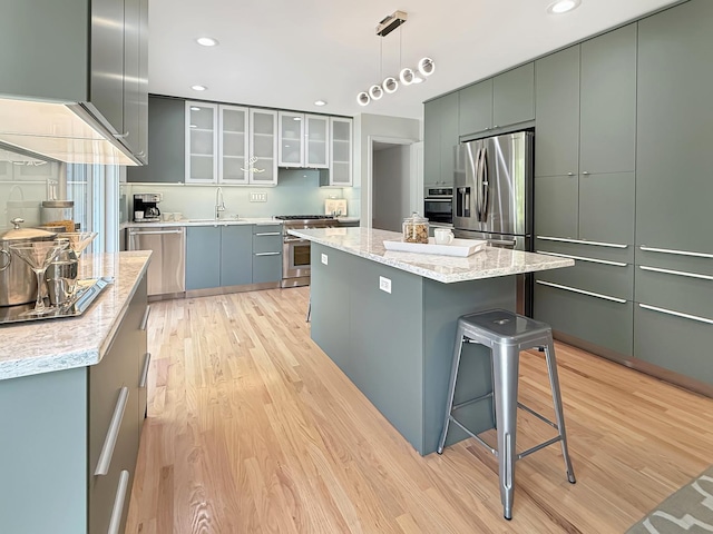 389 Forest Ave, Glen Ellyn, IL 60137 - kitchen with appliances with stainless steel finishes, light wood-type flooring, a kitchen island, hanging light fixtures, and recessed lighting