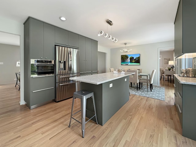 389 Forest Ave, Glen Ellyn, IL 60137 - kitchen featuring appliances with stainless steel finishes, light wood-type flooring, a kitchen island, gray cabinets, and hanging light fixtures