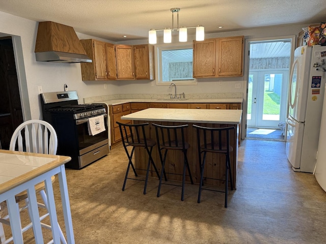 2705 Pine St, Rock Falls, IL 61071 - kitchen featuring stainless steel range with gas cooktop, freestanding refrigerator, custom exhaust hood, light countertops, and light flooring