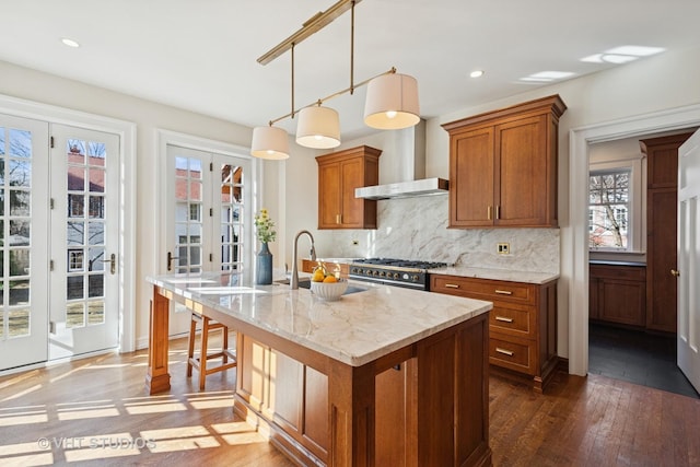1120 Forest Ave, Evanston, IL 60202 - kitchen featuring brown cabinets, dark wood-style floors, wall chimney exhaust hood, decorative backsplash, and a center island with sink