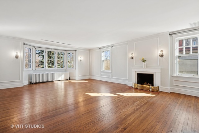 1120 Forest Ave, Evanston, IL 60202 - unfurnished living room featuring radiator heating unit, hardwood / wood-style floors, a decorative wall, a fireplace with flush hearth, and crown molding
