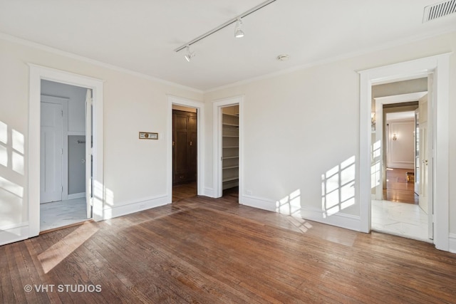 1120 Forest Ave, Evanston, IL 60202 - unfurnished bedroom with wood-type flooring, rail lighting, a spacious closet, crown molding, and a closet
