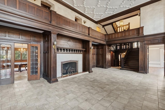 1120 Forest Ave, Evanston, IL 60202 - unfurnished living room featuring a chandelier, a towering ceiling, crown molding, stairs, and a fireplace with raised hearth