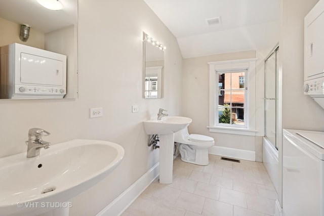 1120 Forest Ave, Evanston, IL 60202 - full bathroom with stacked washing machine and dryer, lofted ceiling, tile patterned flooring, and enclosed tub / shower combo