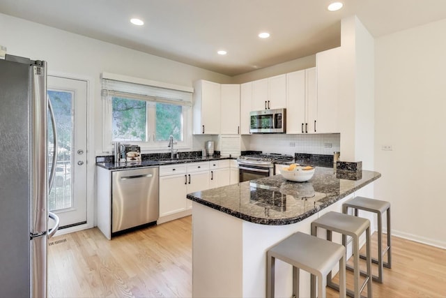 1728 W Terra Cotta Pl Unit D, Chicago, IL 60614 - kitchen with appliances with stainless steel finishes, light wood finished floors, a peninsula, dark stone counters, and white cabinets