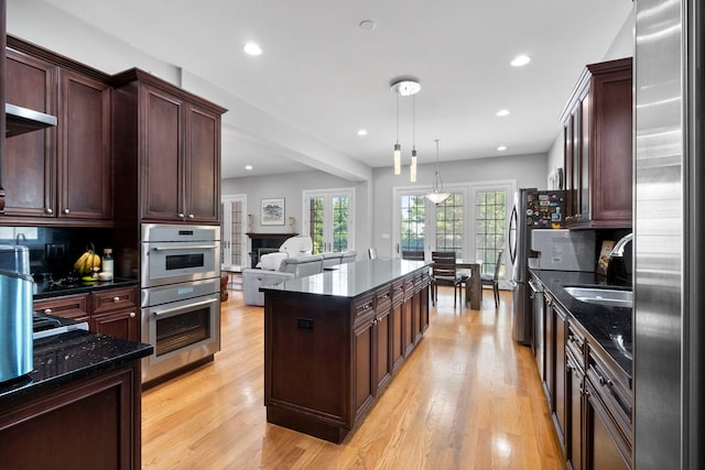 4146 Cardinal Ct, Northbrook, IL 60062 - kitchen with stainless steel appliances, a kitchen island, dark stone countertops, light wood-style flooring, and recessed lighting