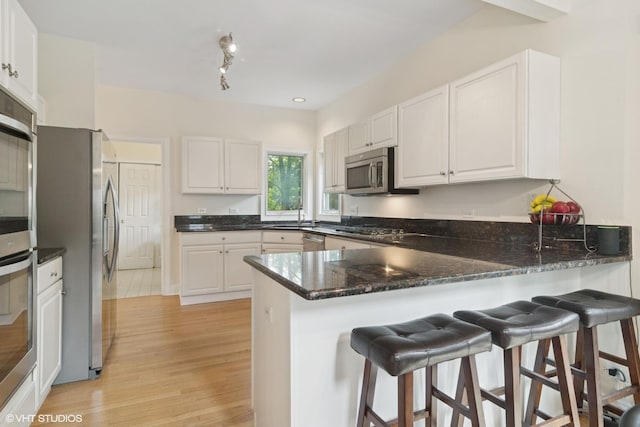 1580 W N St, Palatine, IL 60067 - kitchen featuring appliances with stainless steel finishes, a peninsula, white cabinets, and light wood-type flooring