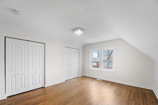 8416 S Bennett Ave, Chicago, IL 60617 - unfurnished bedroom with multiple closets, vaulted ceiling, and wood finished floors
