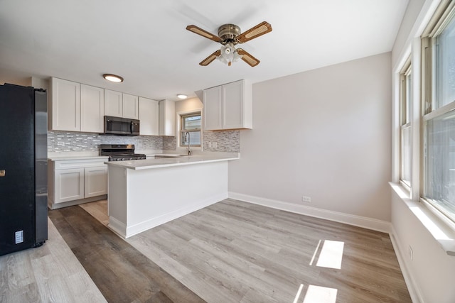 4850 N Clifton Ave, Norridge, IL 60706 - kitchen featuring appliances with stainless steel finishes, ceiling fan, decorative backsplash, light wood-style floors, and white cabinetry