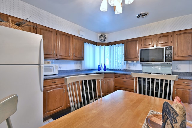 8532 N Olcott Ave, Niles, IL 60714 - kitchen with white appliances, wallpapered walls, dark countertops, brown cabinets, and backsplash