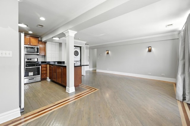 2501 W Touhy Ave Unit 105, Chicago, IL 60645 - kitchen with stainless steel appliances, stacked washer / dryer, crown molding, dark countertops, and open floor plan