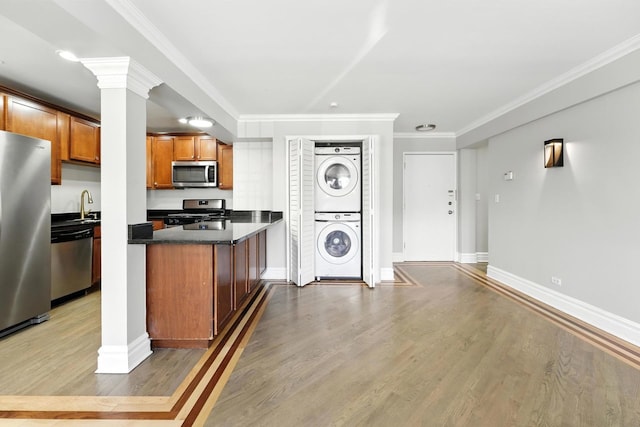2501 W Touhy Ave Unit 105, Chicago, IL 60645 - kitchen with stainless steel appliances, stacked washer / dryer, brown cabinets, dark countertops, and wood finished floors