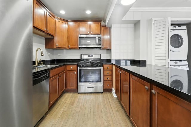 2501 W Touhy Ave Unit 105, Chicago, IL 60645 - kitchen with stainless steel appliances, estacked washer and dryer, crown molding, light wood finished floors, and brown cabinetry