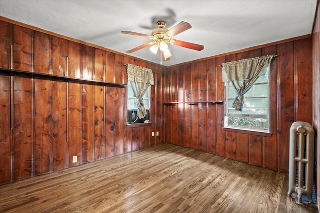 6510 Sinclair Ave, Berwyn, IL 60402 - spare room featuring radiator, wood finished floors, a ceiling fan, and wood walls