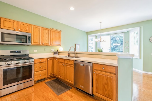 11397 Stonewater Xing, Huntley, IL 60142 - kitchen with appliances with stainless steel finishes, a peninsula, a chandelier, light wood-style flooring, and light countertops