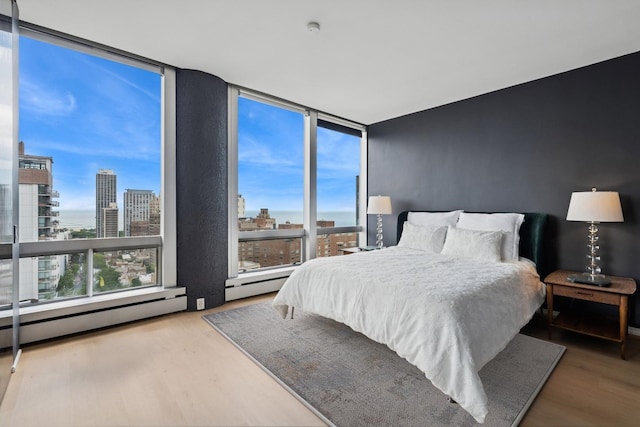 1300 N Astor St Unit 26C, Chicago, IL 60610 - bedroom with wood finished floors, a view of city, floor to ceiling windows, and a baseboard heating unit