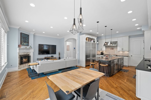 2115 Washington Ave, Wilmette, IL 60091 - dining area with arched walkways, crown molding, light wood-style flooring, a fireplace, and recessed lighting
