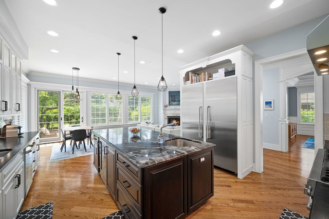 2115 Washington Ave, Wilmette, IL 60091 - kitchen with stainless steel appliances, dark brown cabinets, white cabinetry, a lit fireplace, and ornamental molding