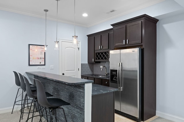 2115 Washington Ave, Wilmette, IL 60091 - kitchen featuring stainless steel fridge, dark brown cabinetry, a kitchen breakfast bar, dark stone countertops, and ornamental molding