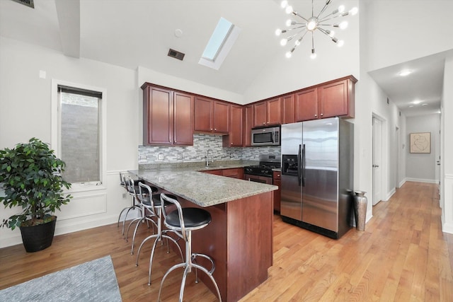 4809 S Wabash Ave Unit 3, Chicago, IL 60615 - kitchen with stainless steel appliances, a peninsula, light wood-style floors, tasteful backsplash, and a breakfast bar
