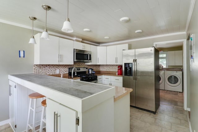 325 W Poplar St S, Heyworth, IL 61745 - kitchen featuring appliances with stainless steel finishes, a peninsula, ornamental molding, backsplash, and washer and dryer