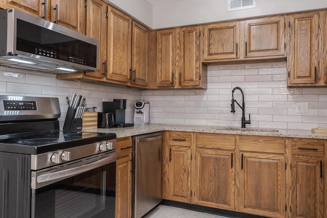 2003 Tracy Dr Unit 1, Bloomington, IL 61704 - kitchen featuring stainless steel appliances, brown cabinets, and tasteful backsplash