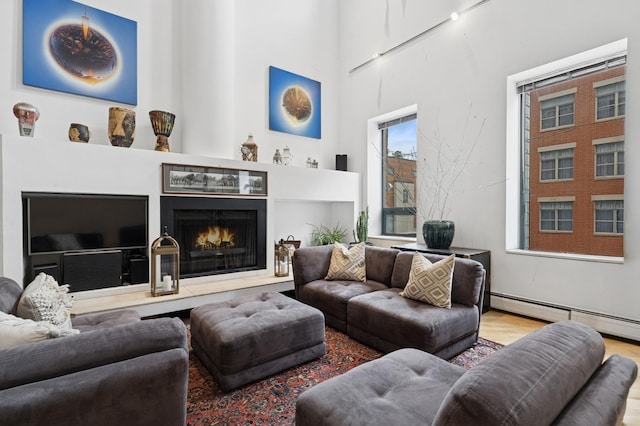 957 W Huron St Unit 2, Chicago, IL 60642 - living room featuring baseboard heating, a lit fireplace, wood finished floors, and a towering ceiling