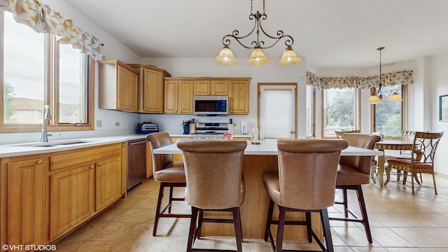 11 Carrington Ct, Hazel Crest, IL 60429 - kitchen with stainless steel appliances, light countertops, a kitchen island with sink, light tile patterned floors, and pendant lighting