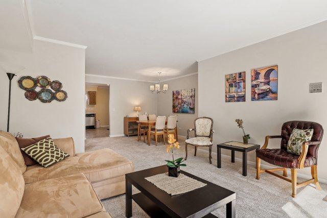 3256 Sanders Rd Unit 4E, Northbrook, IL 60062 - living area with a chandelier, crown molding, and light colored carpet