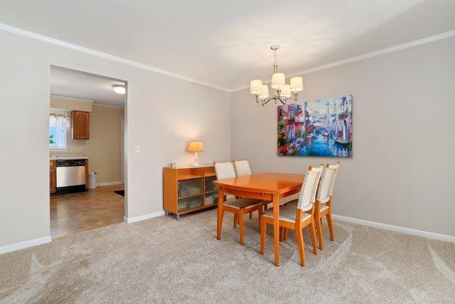 3256 Sanders Rd Unit 4E, Northbrook, IL 60062 - dining space featuring a chandelier, crown molding, and light carpet