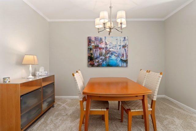3256 Sanders Rd Unit 4E, Northbrook, IL 60062 - dining room featuring a chandelier, light carpet, and ornamental molding