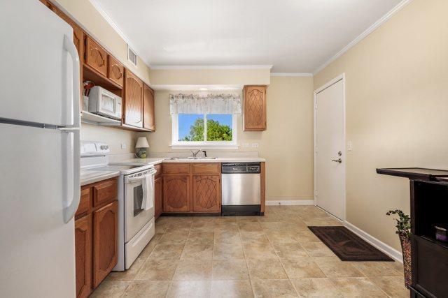 3256 Sanders Rd Unit 4E, Northbrook, IL 60062 - kitchen with white appliances, light countertops, ornamental molding, and brown cabinetry