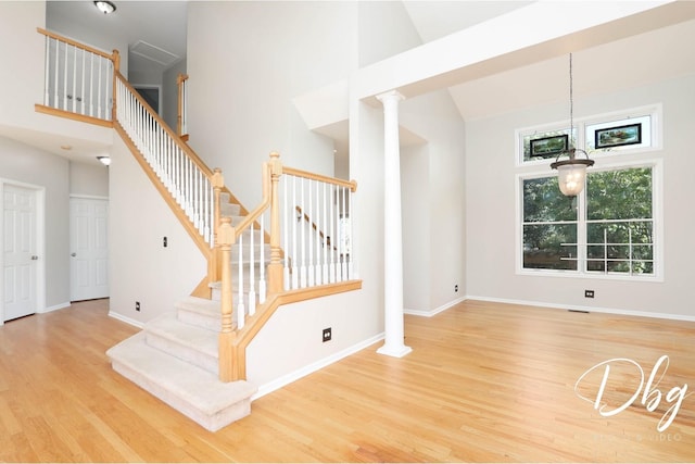 582 Aspen Way, Antioch, IL 60002 - unfurnished living room with a towering ceiling, wood finished floors, ornate columns, and stairway