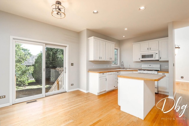 582 Aspen Way, Antioch, IL 60002 - kitchen featuring white appliances, white cabinetry, light countertops, light wood-style flooring, and a kitchen island