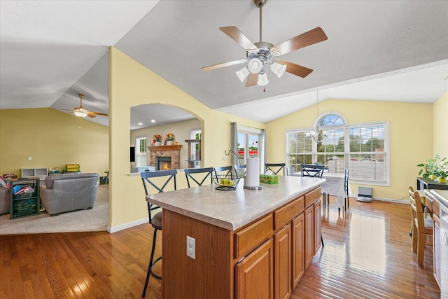 402 Wesley Ave, Savoy, IL 61874 - kitchen with lofted ceiling, a ceiling fan, hardwood / wood-style floors, a kitchen bar, and brown cabinetry