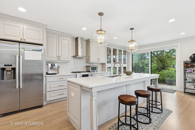 3118 River Falls Dr, Northbrook, IL 60062 - kitchen featuring stainless steel refrigerator with ice dispenser, wall chimney exhaust hood, a center island with sink, light wood finished floors, and hanging light fixtures