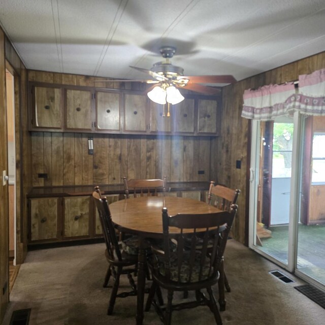 16306 W Canada Rd, Polo, IL 61064 - dining space featuring dark colored carpet, wooden walls, and a ceiling fan