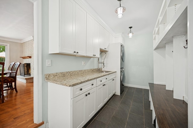 200 W Center Ave, Lake Bluff, IL 60044 - kitchen featuring stacked washer / dryer, white cabinets, light stone countertops, a brick fireplace, and crown molding