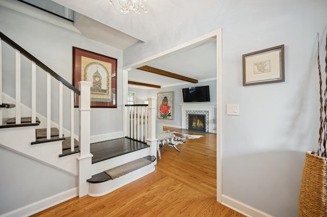 200 W Center Ave, Lake Bluff, IL 60044 - stairway with wood finished floors, beamed ceiling, a tiled fireplace, and a chandelier