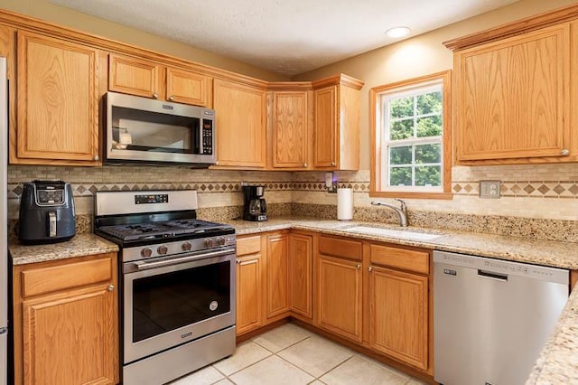 10873 Meadowsweet Ln, Roscoe, IL 61073 - kitchen with appliances with stainless steel finishes, tasteful backsplash, light tile patterned floors, and light stone countertops