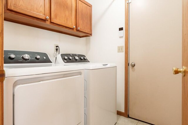 10873 Meadowsweet Ln, Roscoe, IL 61073 - laundry area featuring washer and dryer, cabinet space, and light tile patterned floors