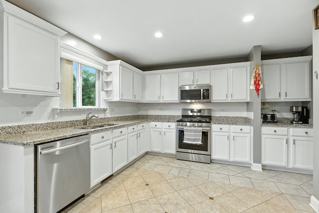 2943 Heather Ln, Montgomery, IL 60538 - kitchen with stainless steel appliances, light tile patterned floors, white cabinetry, backsplash, and light stone countertops