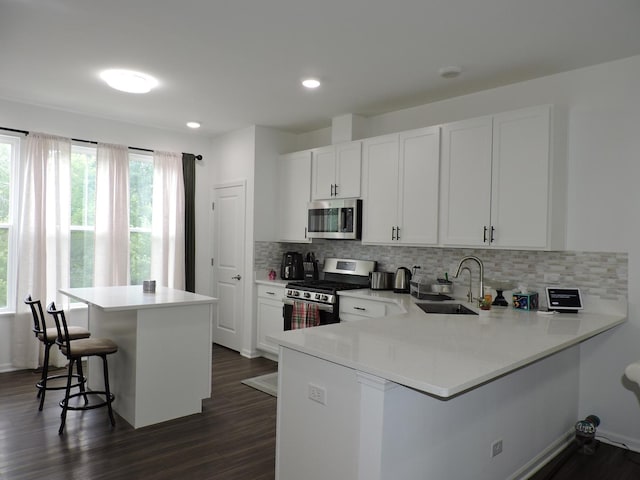 516 Wolverine Dr, Aurora, IL 60502 - kitchen featuring appliances with stainless steel finishes, a breakfast bar, dark wood-type flooring, decorative backsplash, and recessed lighting