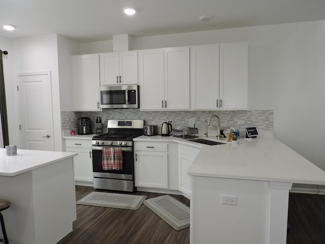 516 Wolverine Dr, Aurora, IL 60502 - kitchen with stainless steel appliances, a peninsula, a breakfast bar, light countertops, and dark wood finished floors